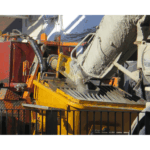 建設現場で、生コン車がシュートからコンクリートを打設している様子。コンクリートの運搬・打込み・締固め作業を象徴する一枚。